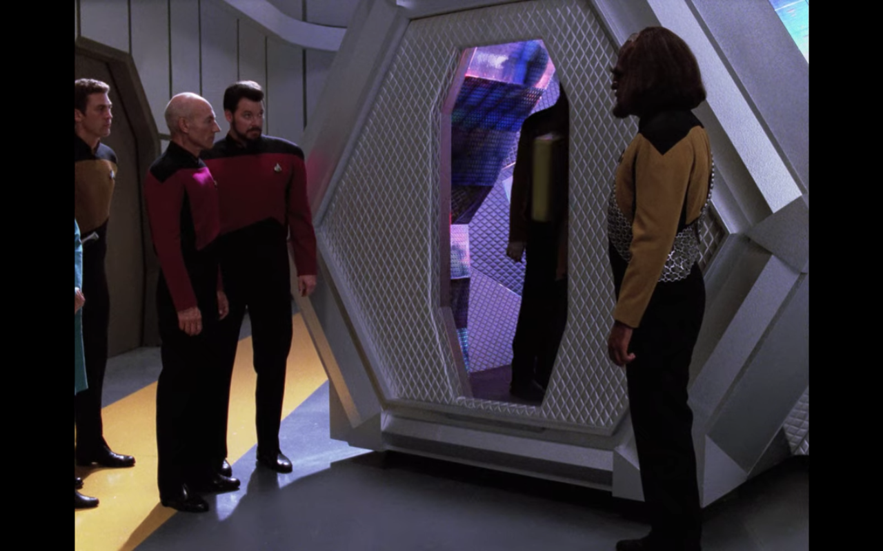 Picard, Riker, and Worf outside a strange silver alien shuttle with purple light inside