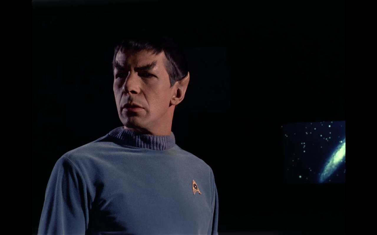 Spock wearing a variation on his usual uniform, in front of a small monitor