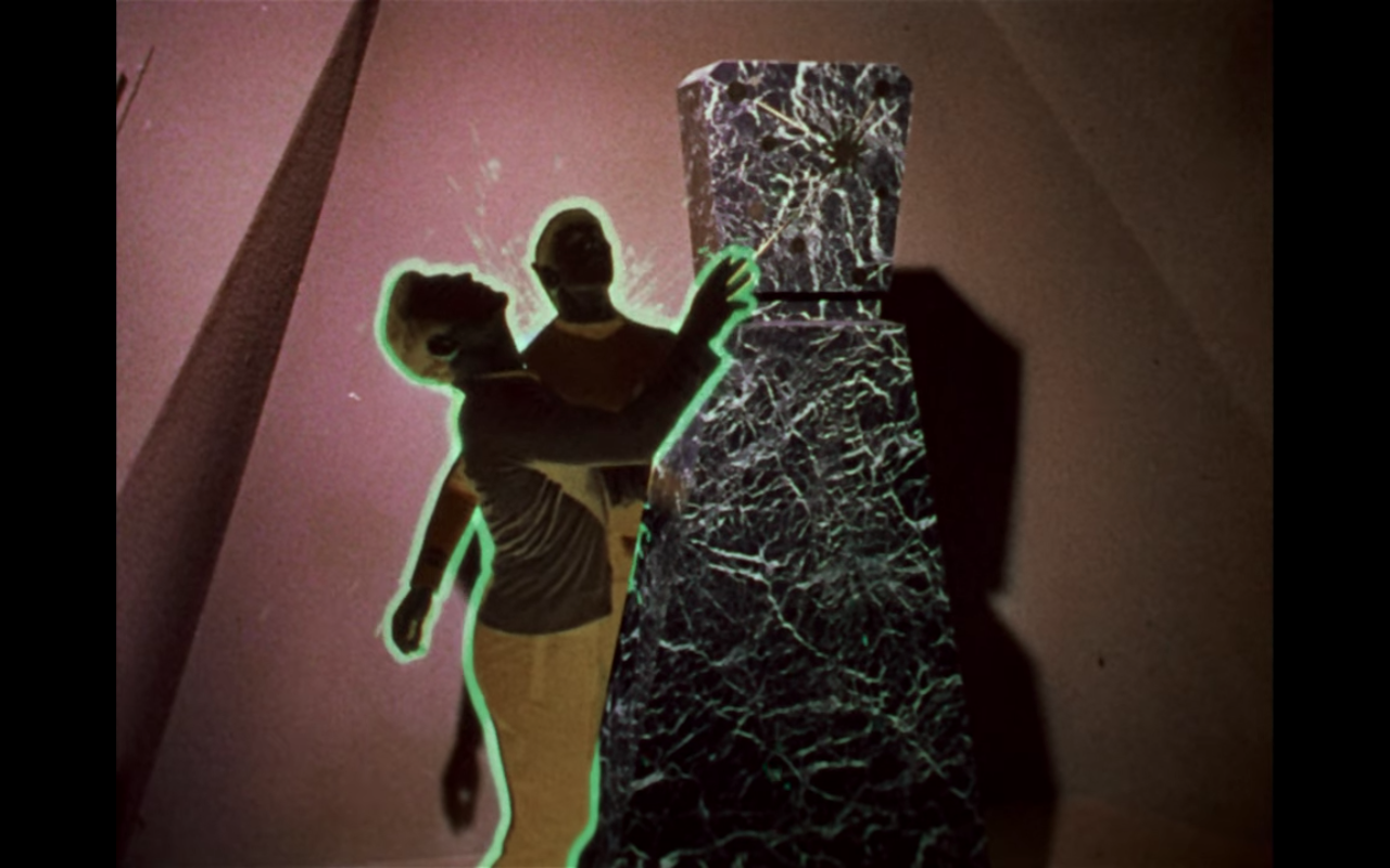Kirk and Spock in photo-negative, while touching a stony obelisk