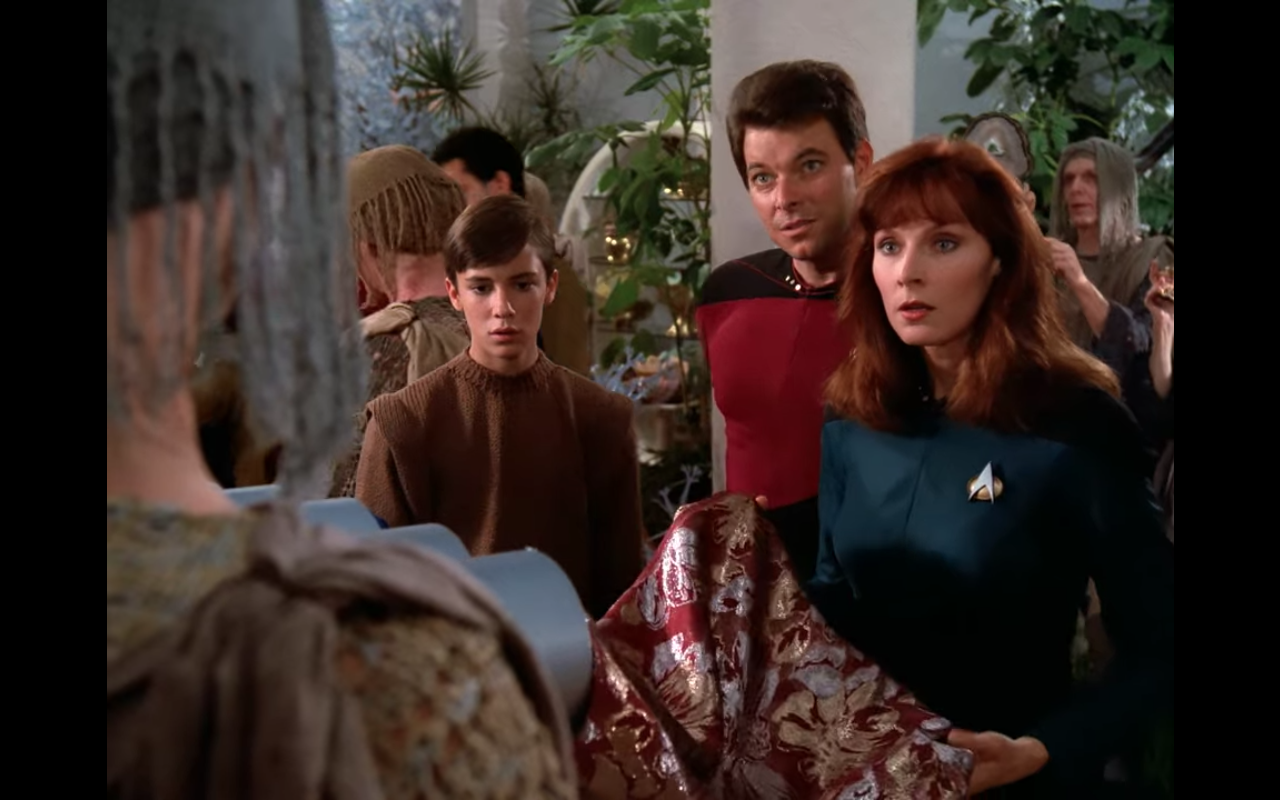 Riker, Beverly, and a very young Wesley in a bazaar