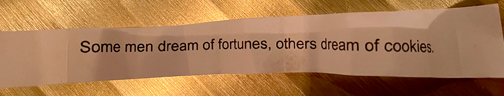 Handmade paper fortune from fortune cookie reading 'Some men dream of fortunes, others dream of cookies'