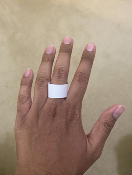 A white paper ring on the middle finger of the back of a left hand.