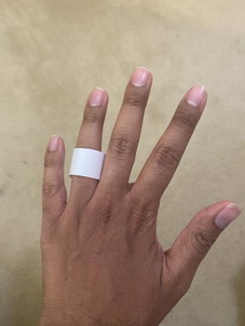A white paper ring on the ring finger of the back of a left hand.